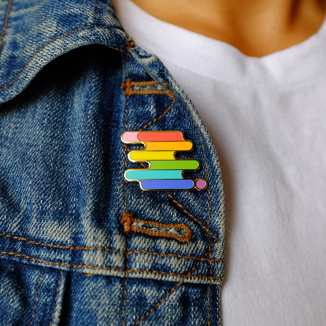 Model wearing the LGBTQ+ Pride Original Flag Enamel Pin on their jacket. LGBTQ+ Pride pin by Bianca Designs