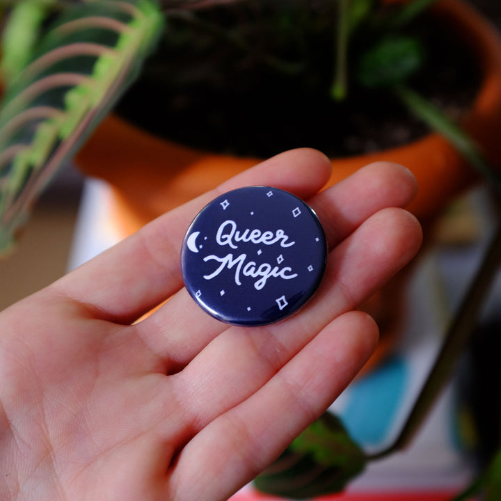 Hand holding the Queer Magic Pinback Button by Bianca Designs.