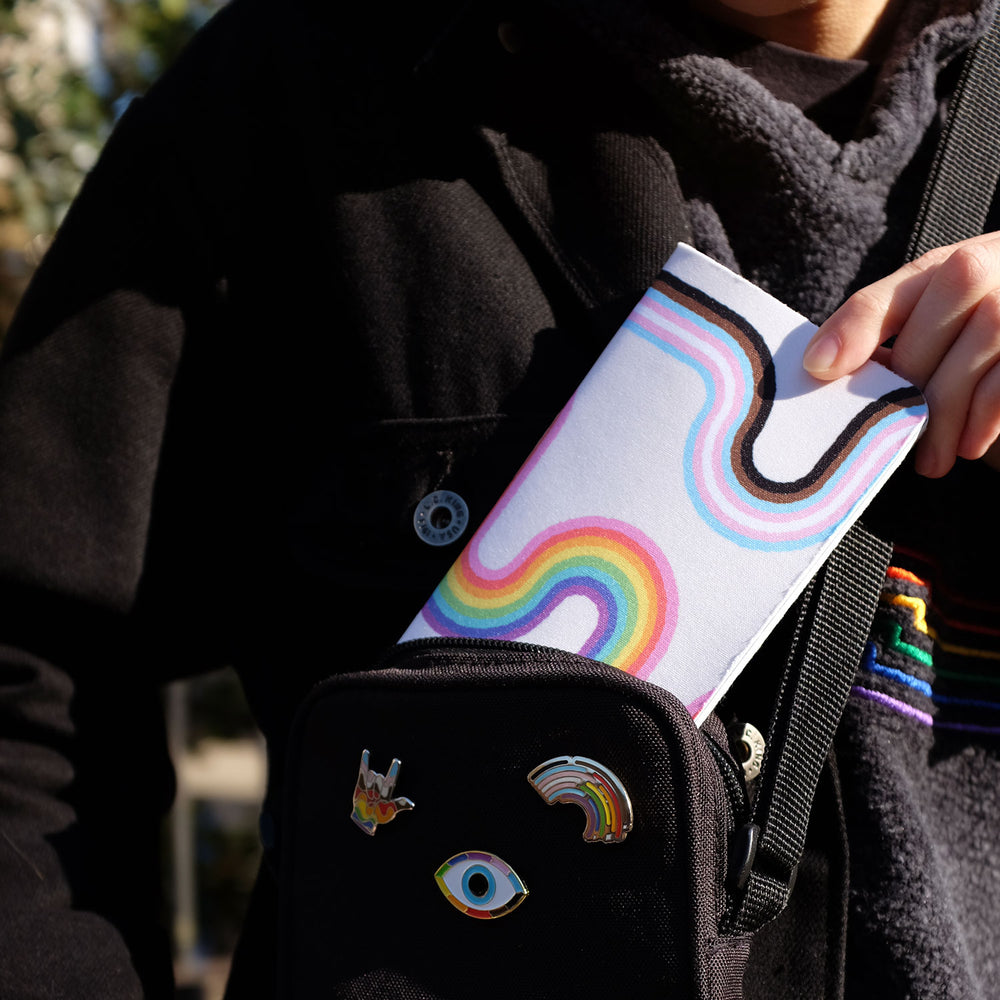 Rainbow Road Inclusive Pride Notebook by Bianca Designs. In this photo the model is taking the pocket notebook out of a small bag.